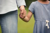 Cropped image of cute  mother and daughter holding hands — Stock Photo