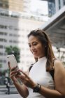 Молода азіатська приваблива жінка використовує смартфон на міській вулиці — стокове фото