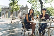 Japanische und chinesische Touristinnen beim Kaffee auf der Terrasse in der Nähe der Puerta de Alcala in Madrid, Spanien. — Stockfoto