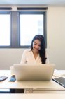 Giovane donna che lavora sul suo computer portatile in ufficio moderno — Foto stock