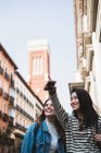 Two beautiful female friends walking in city and pointing — Stock Photo