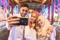 Three young muslims are taking a selfie during night time on a bridge — Stock Photo