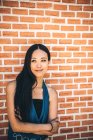 Cheveux longs asiatique femme posant sur brique mur — Photo de stock