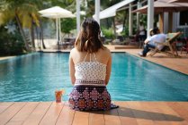 Vue arrière de jeune attrayant asiatique femme détente par piscine — Photo de stock