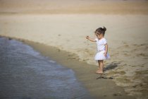 Маленька дівчинка грає з піском на пляжі — стокове фото