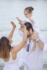 Glückliche junge Familie verbringt Zeit zusammen am Strand — Stockfoto