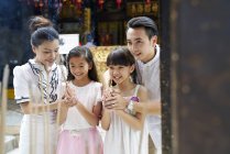 Happy asian family praying together in traditional Singaporean shrine — Stock Photo