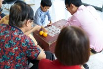 Feliz família asiática a passar tempo juntos e jogar o jogo de tabuleiro — Fotografia de Stock