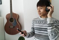Junge erwachsene asiatische Mann mit Smartphone zu Hause — Stockfoto