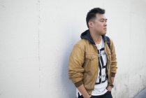 Jeune homme asiatique debout contre le mur — Photo de stock