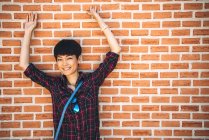 Schöne Chinesin posiert für Kamera gegen Ziegelmauer — Stockfoto
