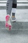 Обрезанное изображение пары ног, бегущих по бетонным ступенькам на улице . — стоковое фото