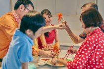 Happy asian family eating together at table at chinese new year — Stock Photo