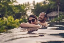 Joven pareja asiática relajándose en una piscina - foto de stock