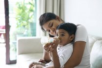 Ásia mãe alimentando ela filho a partir de um leite garrafa — Fotografia de Stock