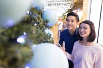 Young attractive asian couple together shopping in mall at christmas — Stock Photo