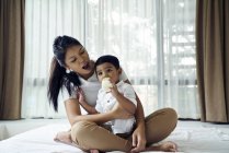 Asiatique mère montres comme son fils se nourrit sur lait bouteille — Photo de stock