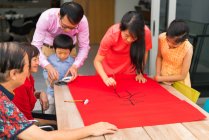 Счастливые азиатские семьи рисуют иероглифы каллиграфии — стоковое фото