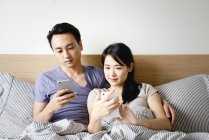 Adulto asiático casal juntos usando smartphones em casa — Fotografia de Stock