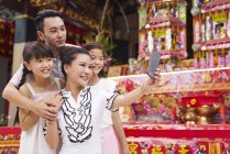 Happy asian family spending time together in traditional Singaporean shrine and taking selfie — Stock Photo