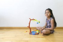 Молода маленька мила азіатська дівчинка грає з іграшками на підлозі — стокове фото