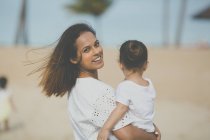 Glückliche junge Mutter und Tochter verbringen Zeit zusammen am Strand — Stockfoto