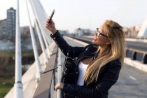 Портрет красивой молодой женщины с помощью мобильного телефона на улице. — стоковое фото
