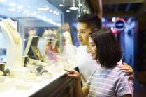Young asian couple looking at jewelry in shop — Stock Photo