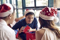 Happy young asian friends celebrating christmas together in cafe and sharing gifts — Stock Photo