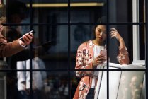 Jolie femme chinoise cheveux longs en utilisant smartphone à travers la fenêtre — Photo de stock