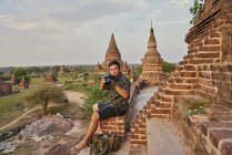 Joven tomando fotos alrededor del antiguo templo de Pyathadar, Bagan, Myanmar - foto de stock