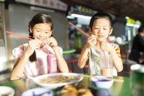 Маленькие азиатские дети играют с соломинками — стоковое фото