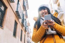 Молода приваблива азіатська жінка використовує смартфон на вулиці — стокове фото