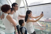 Una familia asiática de tres generaciones se toma una selfie en un centro comercial - foto de stock