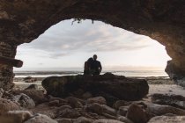 Visão traseira do jovem casal em uma praia em Bali dentro de uma caverna — Fotografia de Stock