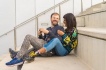 Jovem atraente casal multirracial sentado em escadas — Fotografia de Stock