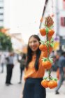 Молода азіатка показує мандарини на камеру — стокове фото