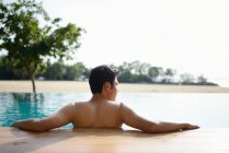 Vue arrière de jeune homme asiatique attrayant relaxant dans la piscine — Photo de stock
