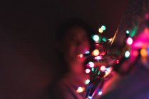 Junge Asiatin entspannt zu Hause mit Weihnachtsgirlanden — Stockfoto