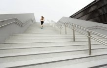 Eine junge asiatische Läuferin läuft in Singapore eine Treppe hinauf. — Stockfoto