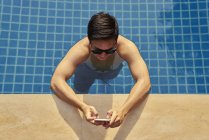 Молодий чоловік фотографує зі своїм мобільним телефоном у басейні — стокове фото