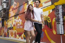 Young attractive asian couple hugging and walking on street — Stock Photo