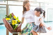 Little asian girl presenting flowers to her mom — Stock Photo