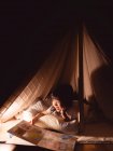 Cute Little Girl is Reading a Book in Tent — Stock Photo
