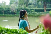 Porträt einer Frau, die beim Spazierengehen im botanischen Garten Musik hört — Stockfoto