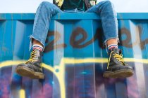Cropped image of funky woman sitting on container — Stock Photo