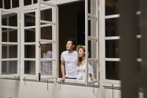 Felice giovane coppia asiatica guardando fuori dalla finestra — Foto stock