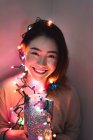Joven mujer asiática relajándose en casa con guirnalda de Navidad - foto de stock