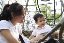 Азіатська мати зв'язується з сином на дитячому майданчику — стокове фото