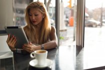 Porträt einer schönen jungen Frau, die ihr digitales Tablet im Café benutzt. — Stockfoto